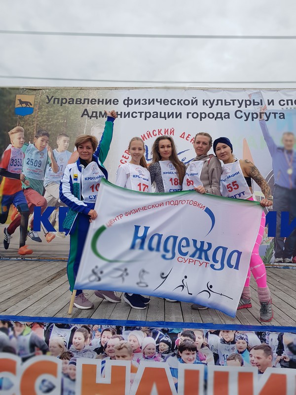на фотографии сотрудники учреждения, принявшие участие в забегах в рамках Всероссийского дня бега «Кросс Нации 2022», с флагом МБУ ЦФП «Надежда».